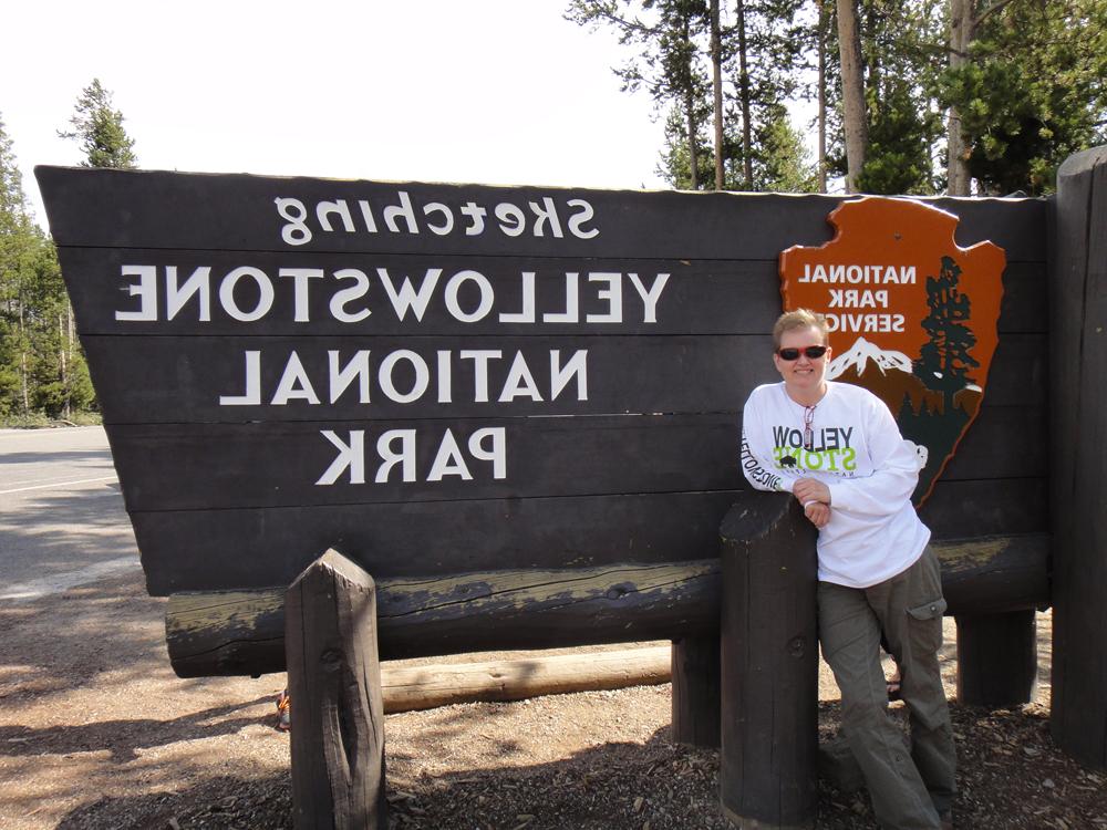 苏西加纳 standing by Yellow Stone National Park Sign